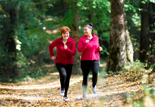 スポーツ ウエアを着ていると山で森で実行されている母と娘 - active seniors women senior adult mature adult ストックフォトと画像