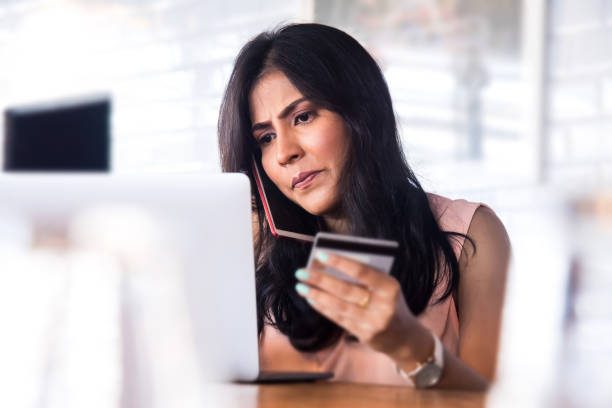 Young Asian woman having problem using her credit card for internet banking