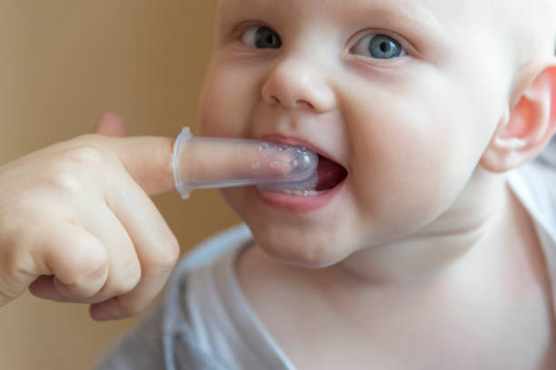 istock Mom brushes baby's teeth with a brush that fits on her finger 1063008978