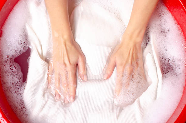 Women washing white sweater clothes in basin enemale powdered detergent, top view