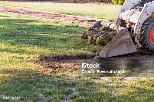 istock Small Bulldozer Removing Grass From Yard Preparing For Pool Installation 1063017688