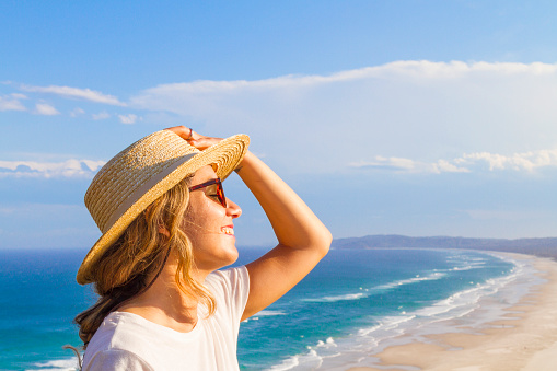 Young summer woman wearing hat and sunglasses at the beach