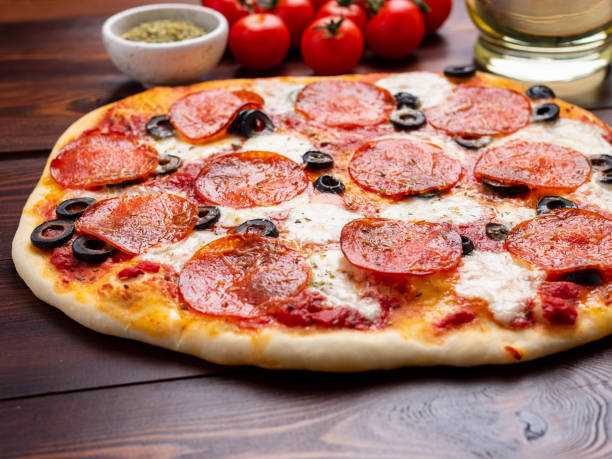 hot homemade italian pepperoni pizza with salami, mozzarella and olives on a dark brown wooden table - oregano freshness herb brown imagens e fotografias de stock