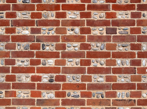 Part of a wall featuring alternating rows of brick and flint pebbles in North Norfolk, England.