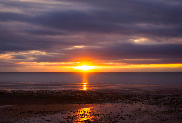 A glowing orange sunset over The Wash in Eastern England. The view is from Hunstanton in West Norfolk over to the Lincolnshire coast and is at low tide.
