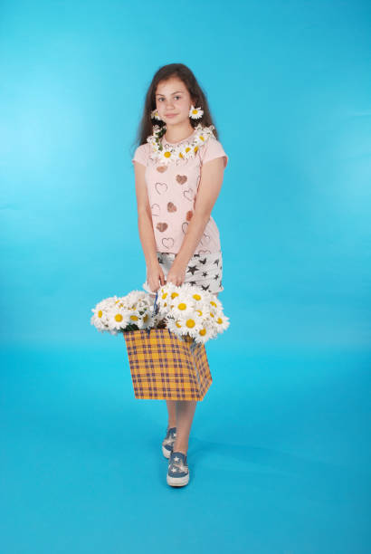 Beautiful girl with chamomile wreath on blue background.