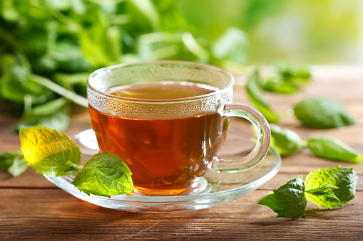 cup of tea with mint leaves on wooden table