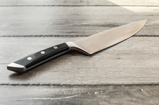 Chef's knife on wooden boards desk.