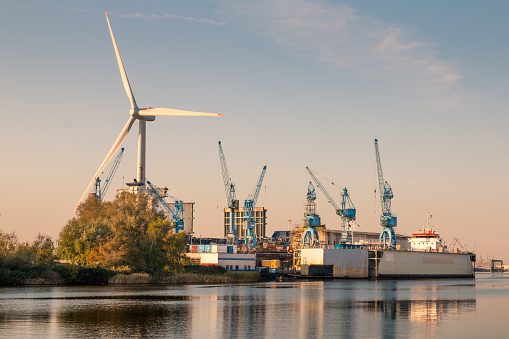 View of a shipyard in northern Germany with a wind turbine in the background.