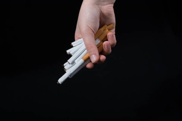 istock Hand is giving out bundle of cigarettes on black 1063037890