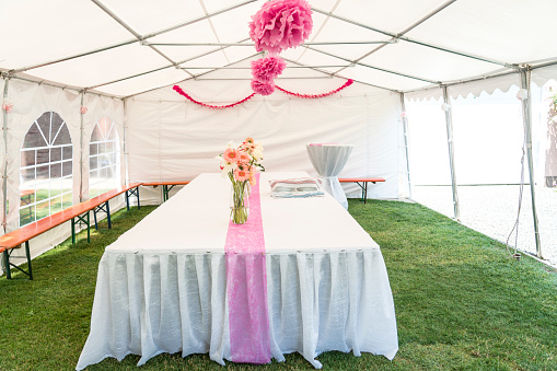 Large tent prepared for wedding celebration with table on the grass.