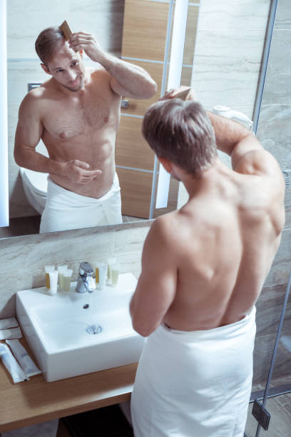 istock Bearded handsome man with nice muscle body combing his hair 1063044348