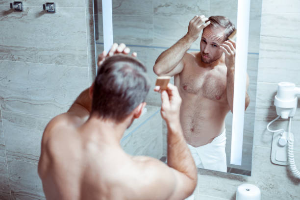 istock Athletic handsome man combing his hair standing in the bathroom 1063044374