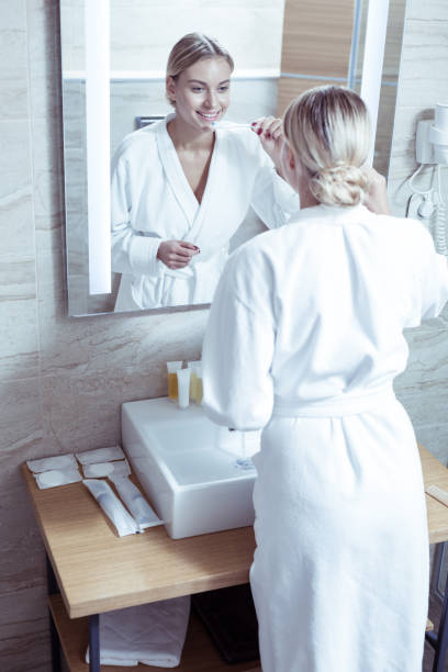 istock Appealing good-looking woman wearing white bathrobe brushing teeth 1063044466