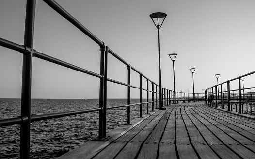A black and white picture of a pier in the grand promenade of Limassol.