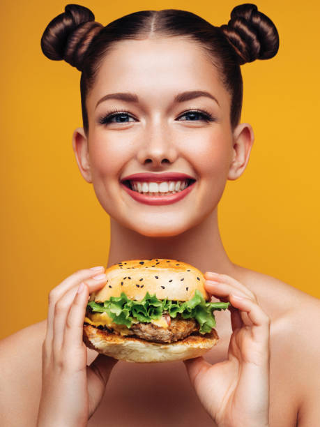 istock Smiling young woman holding burger 1063058070