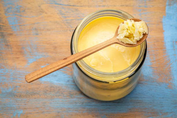 ghee in jar and spoon jar and spoon of ghee (clarified butter) on grunge wood - top view ghee stock pictures, royalty-free photos & images
