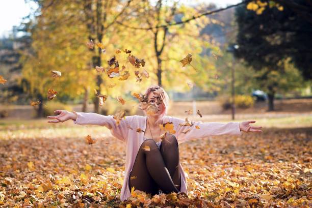 istock Young woman throws fall leaves in park over her face 1063063362