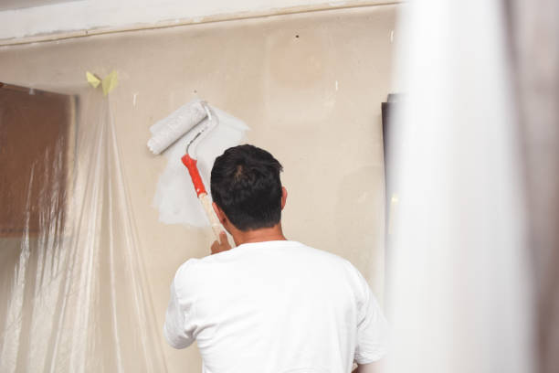 istock Man painting wall at home with painting roller 1063064932