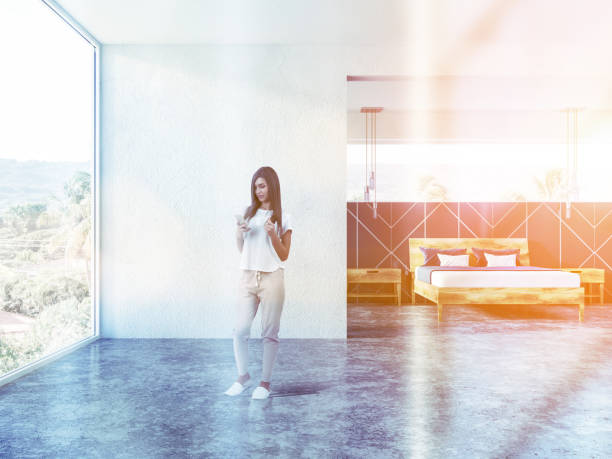 istock Woman with phone in white panoramic bedroom 1063079654