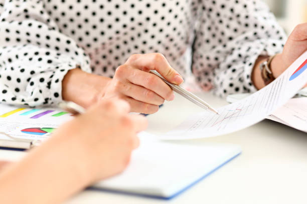 istock Female arm holding silver pen point in financial graph 1063104570