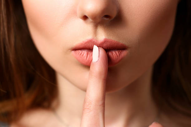 istock Female put finger to closed red lips asking keep silent 1063105722