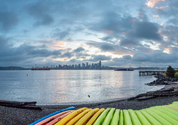 istock Wide Angle View of Multiple Kayaks Sorted on the Beach with Seattle Skyline in the background 1063133716