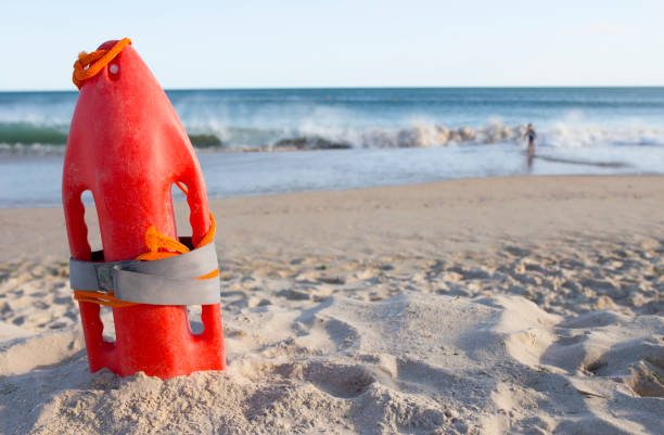 Orange rescue buoy planted on sand beach. Little boy close to the waves at the bottom Orange rescue buoy planted on sand beach. Little boy close to the waves at the bottom. Hazardous scene buoy stock pictures, royalty-free photos & images