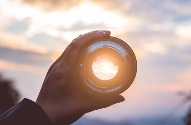 istock Hand holding camera lens at sunset 1063143938