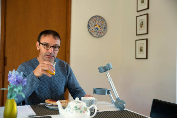 istock Man with crutches having breakfast at home 1063168036