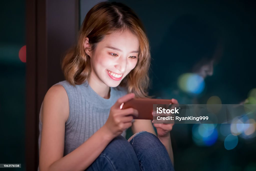 woman play mobile game woman play mobile game happily indoor at night Mobile Phone Stock Photo