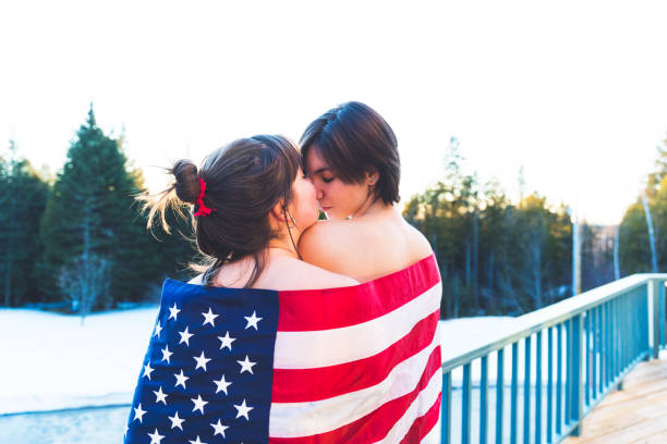 istock Lesbian Couple Wrapped in US flag standing at their balcony 1063197322