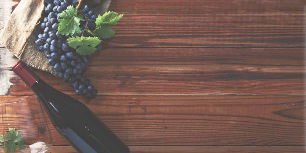 istock Red wine and grapes. Wine and grapes in vintage setting with corks on wooden table Top view. 1063206500