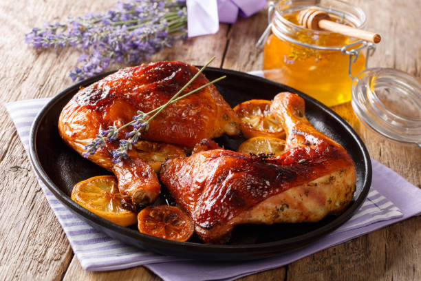 French food: fried quarters chicken legs with lavender honey, spices and lemon close-up. horizontal French food: fried quarters chicken legs with lavender honey, spices and lemon close-up on a plate on the table. horizontal chicken leg stock pictures, royalty-free photos & images