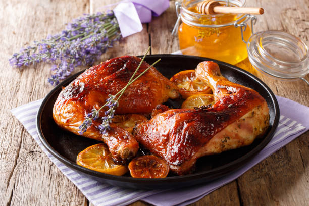 Delicious French food: grilled quarter chicken legs with lavender honey, spices and lemon close-up. horizontal Delicious French food: grilled quarter chicken legs with lavender honey, spices and lemon close-up on a plate on the table. horizontal chicken leg stock pictures, royalty-free photos & images