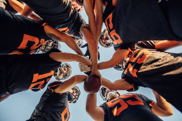 american football-spieler huddling während der auszeit - köpfe zusammenstecken stock-fotos und bilder