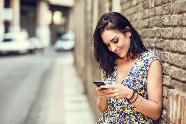 istock Smiling young woman using her smart phone outdoors. 1063208712