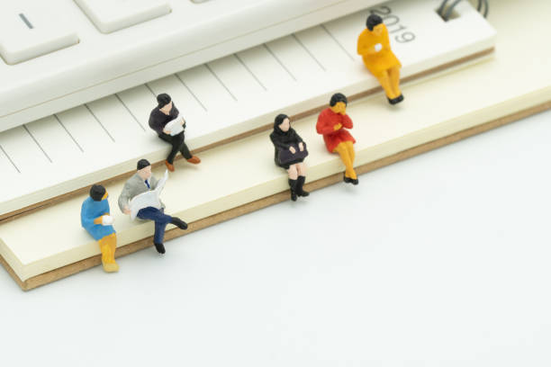 Miniature people sitting on Note Book placed white background. meeting or Discussion using as background business concept with copy space and white space for your text or  design.