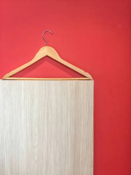 Clothes hanger isolated on red and wooden wall background.