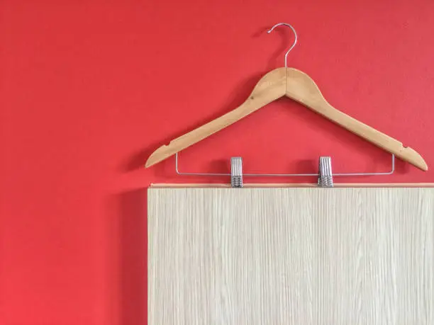 Clothes hanger with steel clip isolated on red and wooden wall background.