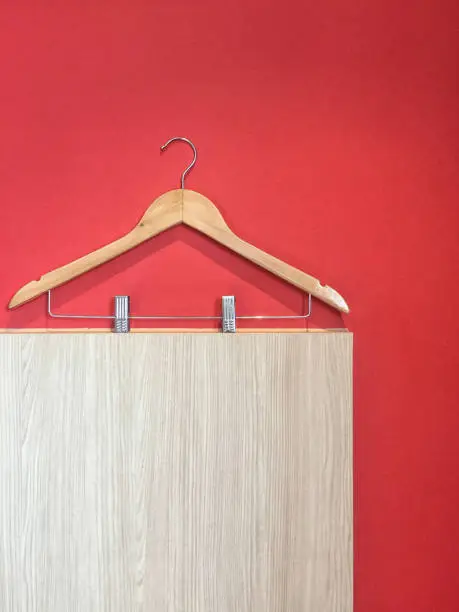 Clothes hanger with steel clip isolated on red and wooden wall background.