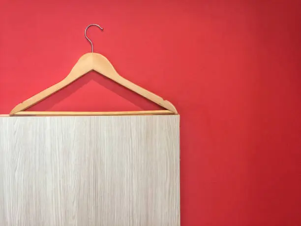 Clothes hanger isolated on red and wooden wall background.