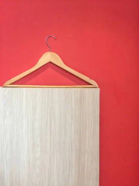 Clothes hanger isolated on red and wooden wall background.