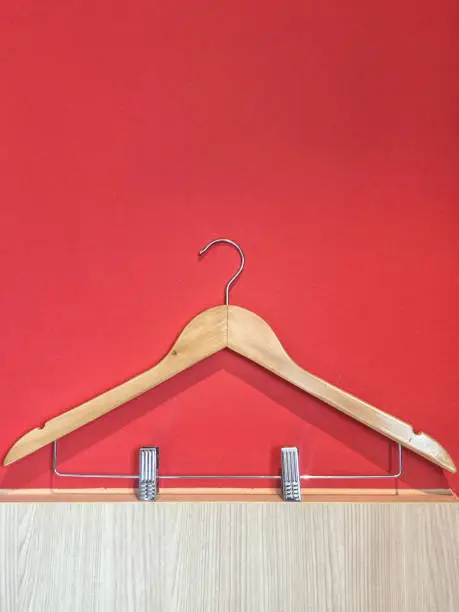 Clothes hanger with steel clip isolated on red and wooden wall background.