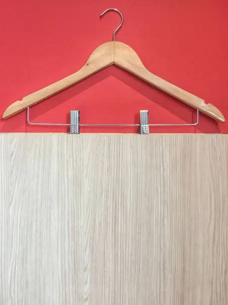 Clothes hanger with steel clip isolated on red and wooden wall background.