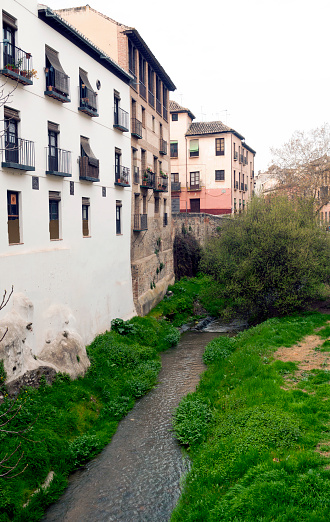 Creek passing by the old houses with a balcony facade in the Spanish city of Granada