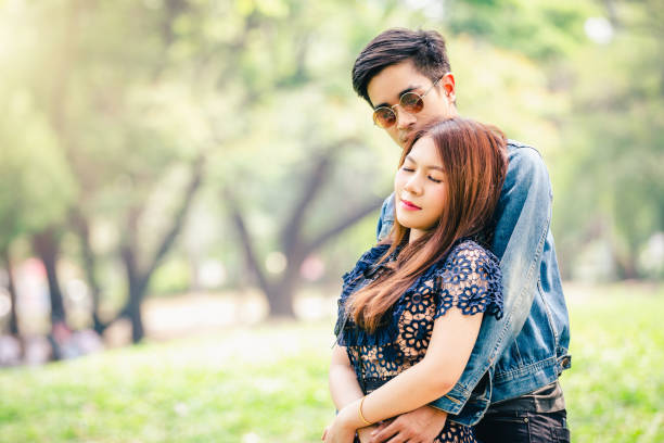 istock Closeup hand asian couple hug loving under tree in park 1063230990