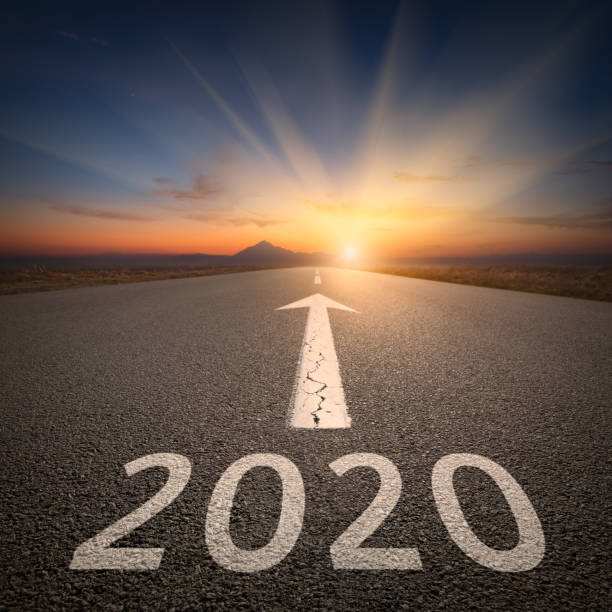 Driving to upcoming 2020 on open road at sunrise Upcoming 2020 new year on empty highway leading to the mountains through the desert against the rising sun. 2020 stock pictures, royalty-free photos & images
