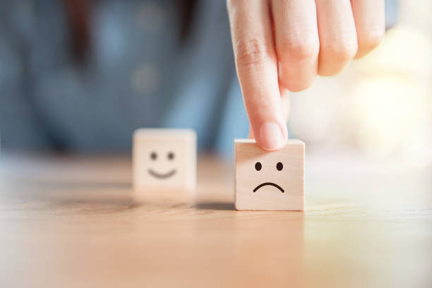 Service rating, satisfaction concept. Close up customer hand choose sad face and blurred smiley face icon on wood cube, Service rating, satisfaction concept. two objects photos stock pictures, royalty-free photos & images