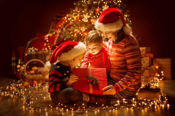 boże narodzenie rodzina otwarcie oświetlenie present gift box pod xmas tree, happy mother children - christmas child baby surprise zdjęcia i obrazy z banku zdjęć